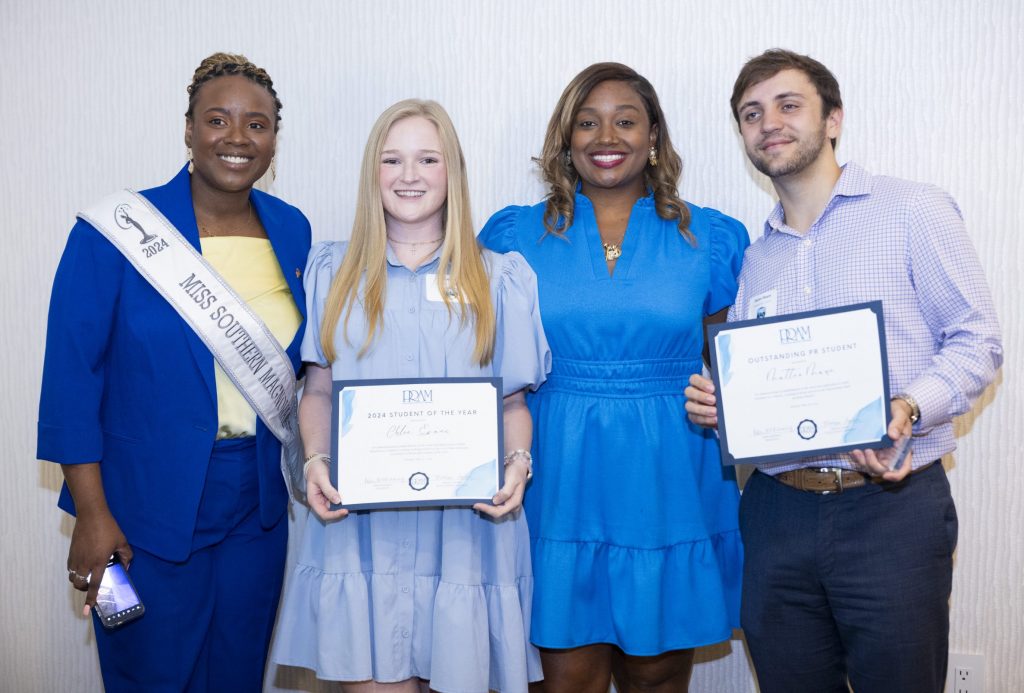 Four people, including two black women and a white man and white woman, standing smiling.